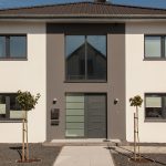 Witte woning met donkergrijze kozijnen en een voordeur met glas