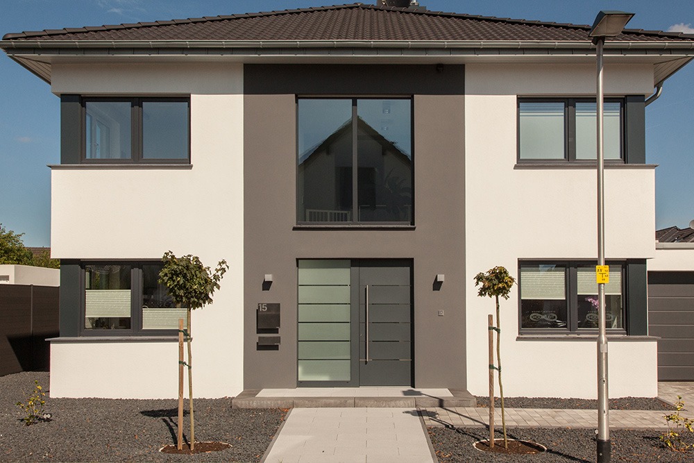 Witte woning met donkergrijze kozijnen en een voordeur met glas