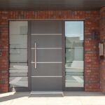 Antracietgrijze voordeur met glazen zijlichten in een bakstenen gevel