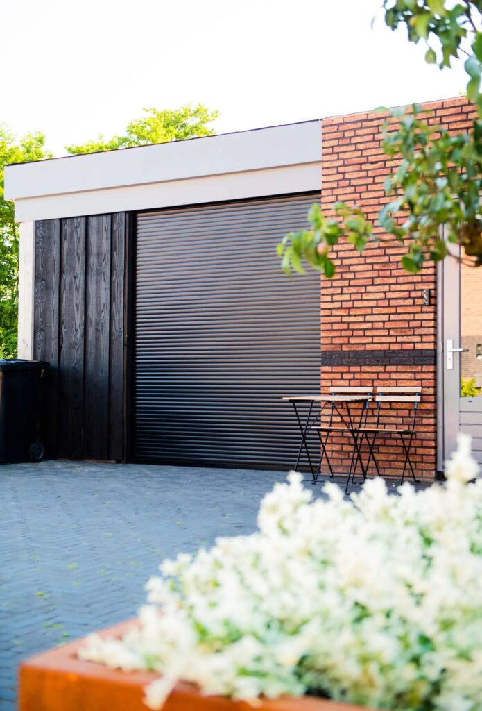 Donker rolluik aan een woning met terras en plantenbak