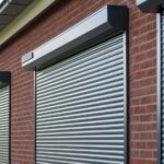 Grijze rolluiken met rolluikkasten voor de ramen van een bakstenen woning